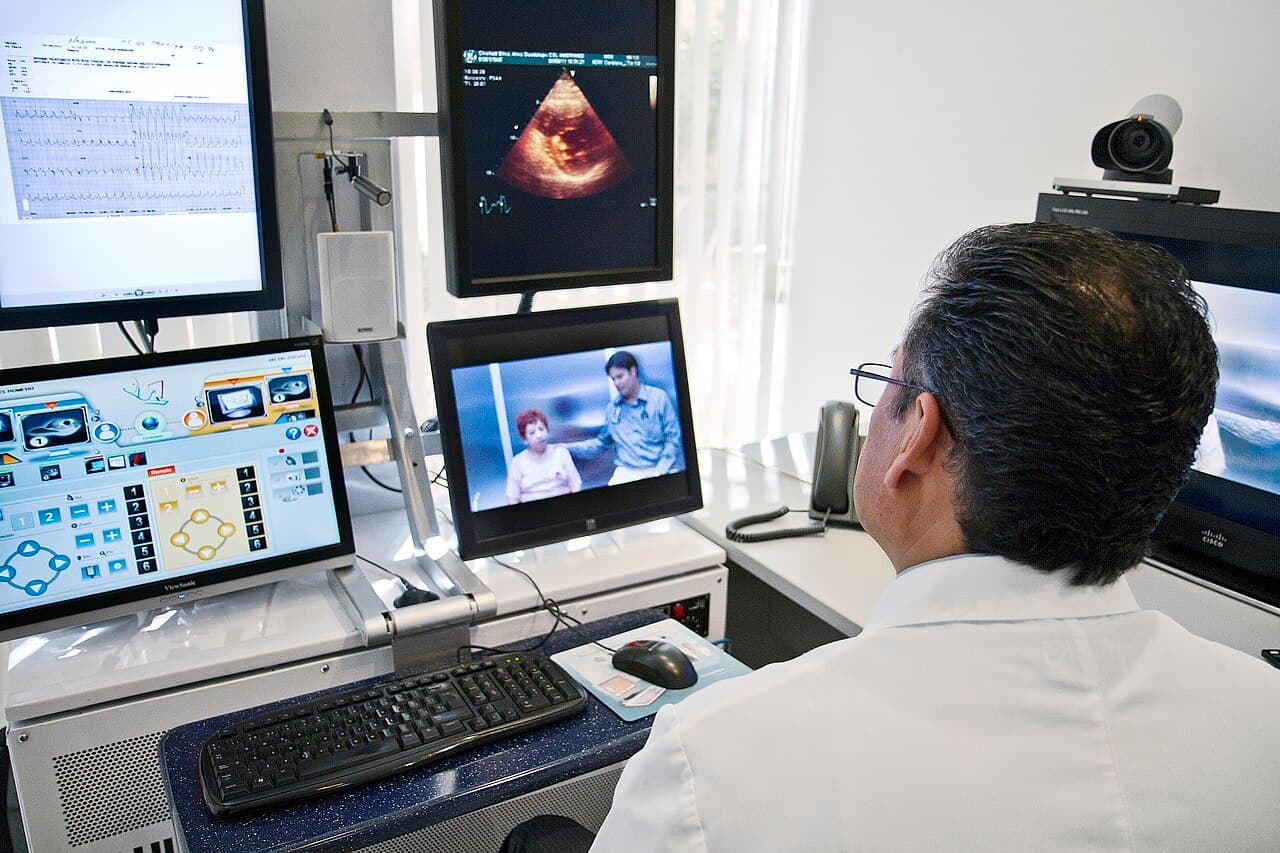 A clinician conducting a remote telemedicine consultation from a hospital desk